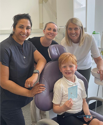Three of the team with a young patient in the dental chair